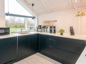 A modern kitchen with black cabinets, a built-in oven, and a coffee maker.