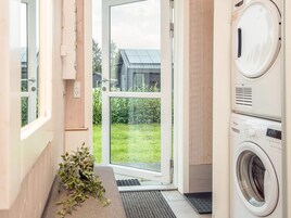 Un lavadero con lavadora, secadora y una puerta que da a un jardín.