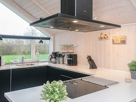 Una cocina moderna con una isla central, estufa integrada y un amplio ventanal con vistas al exterior.