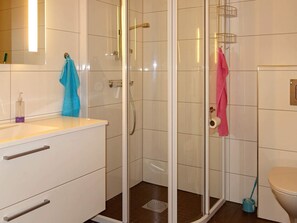 A bathroom with a glass-enclosed shower, a toilet, and a sink with a soap dispenser. - Holiday Home in FÃ¥vang (Farsund)