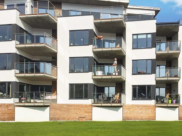 A multi-story residential building with balconies, large windows, and a wooden facade. - Holiday Home in FÃ¥vang (Farsund)