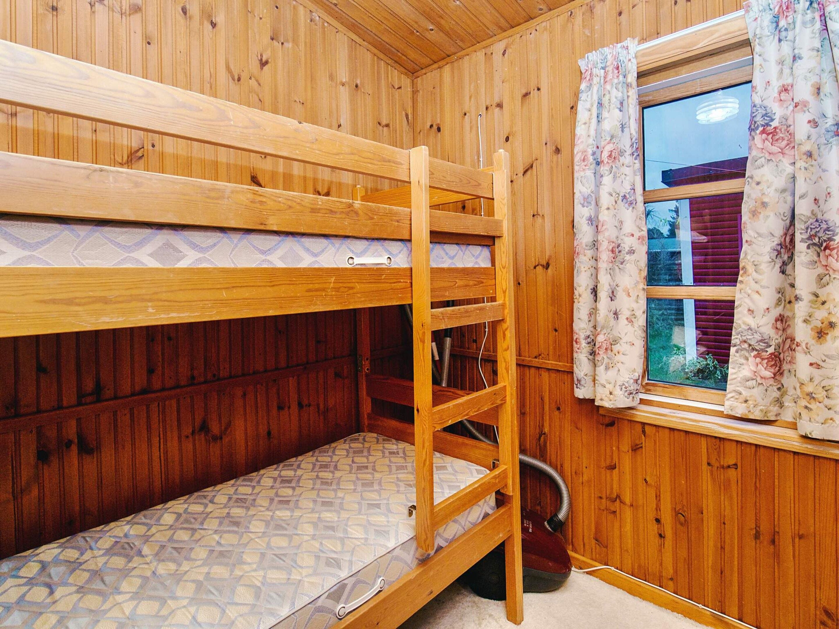 Una cama litera con colchón y escalera de madera.