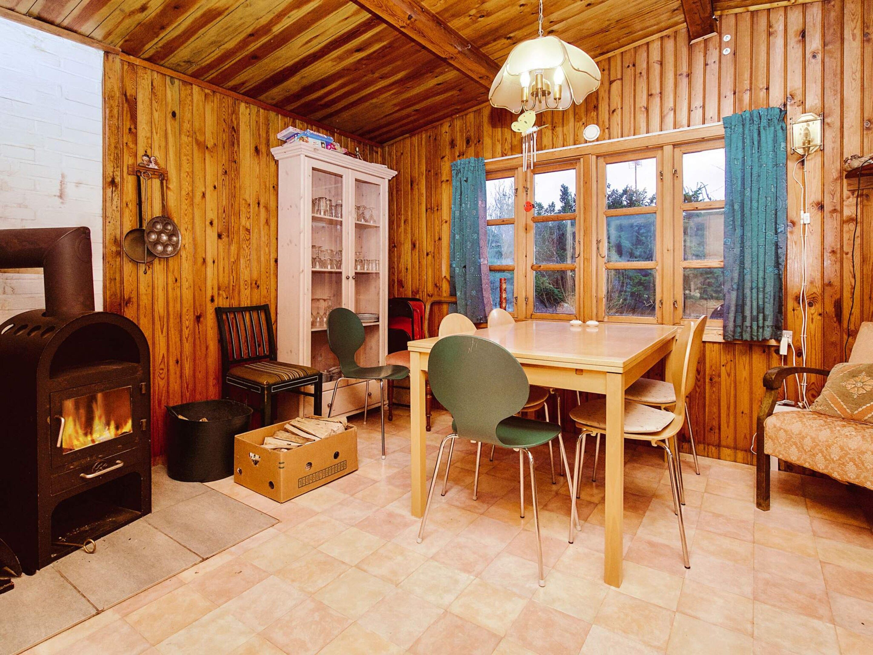 A cozy cabin interior with a wood stove, dining table, chairs, and a sofa.