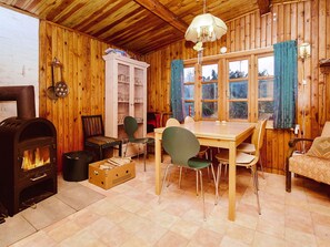 L’intérieur d’un chalet accueillant, avec un poêle à bois, une table à manger, des chaises et un canapé.
