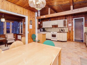 Un interior rústico de madera con comedor, cocina y un amplio ventanal.
