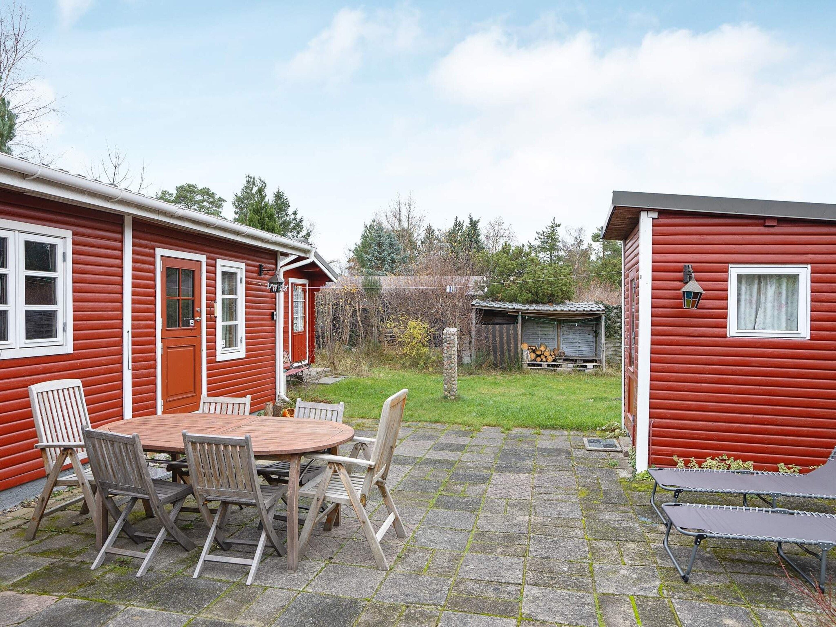 Una casa de madera roja con un porche y una mesa con sillas.
