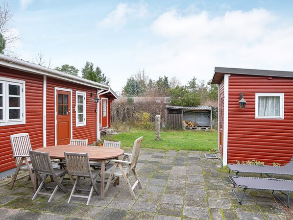 Una casa de madera roja con un porche y una mesa con sillas.