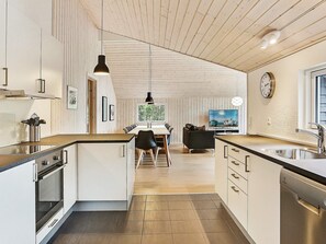 A modern kitchen with a central island, wooden ceiling, and a dining area with a view. - 5 Star Holiday Home in Tisvildeleje (Tisvildeleje)