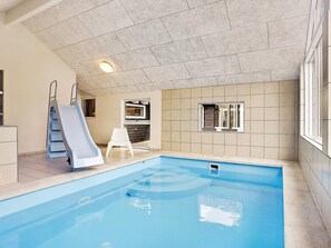 An indoor swimming pool with a slide, a small chair, and a window. - 5 Star Holiday Home in Tisvildeleje (Tisvildeleje)