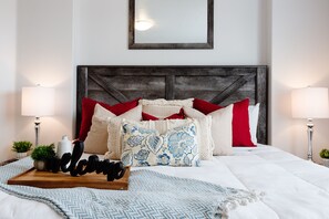 A neatly made bed with a wooden headboard, a tray with 'welcome' sign, and two bedside lamps.