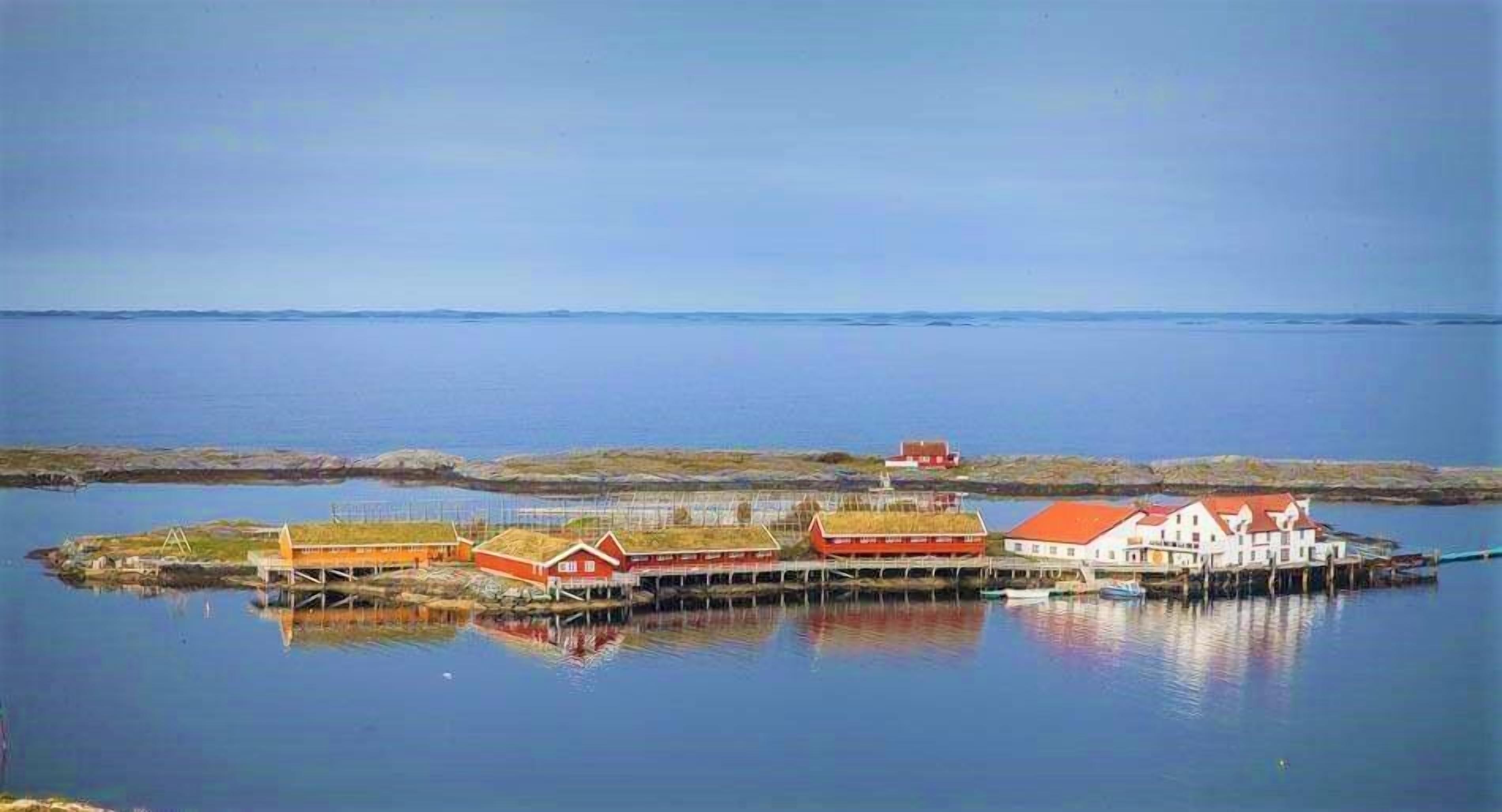 A coastal village with buildings on stilts over water, a clear sky, and calm sea.