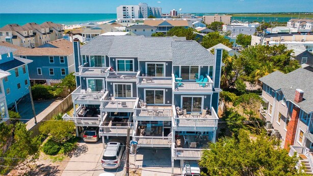 Une propriété en bord de mer, composée de plusieurs étages, dotée de balcons, d’une piscine et offrant une vue sur l’océan.