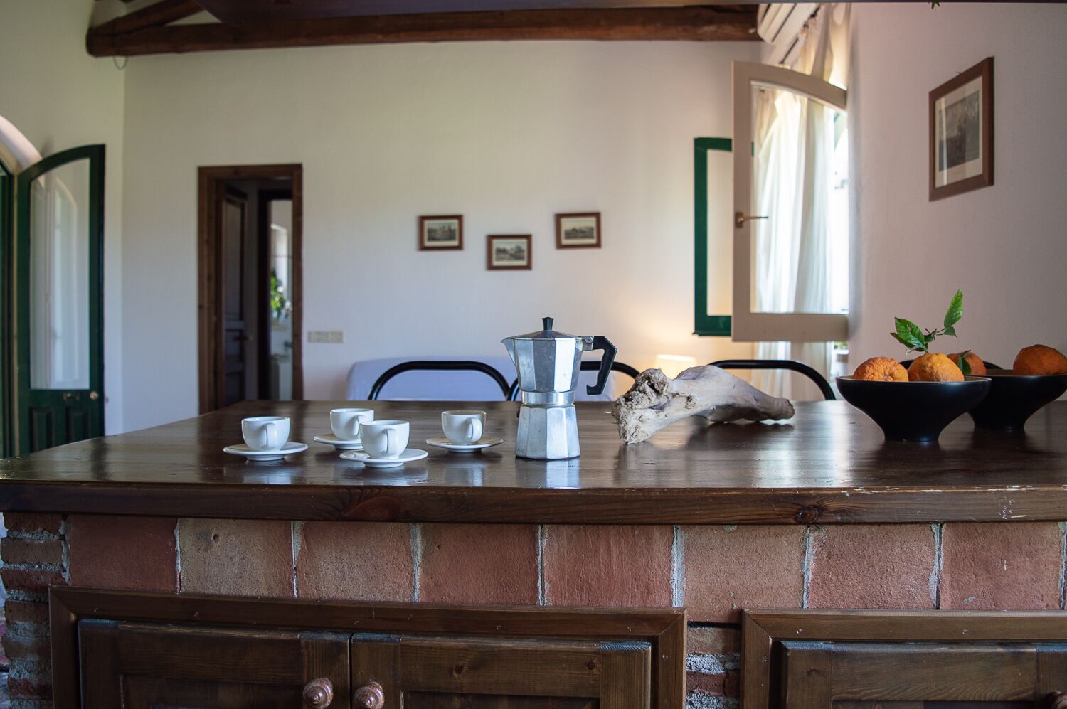 Et rustikt køkken med en murstensbordplade, en kaffemaskine og en skål med appelsiner.