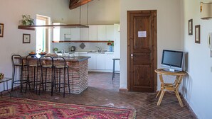 A kitchen with white cabinets, a brick island, and a wooden ceiling. - Tenuta San Calogero (Augusta)