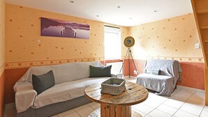A cozy living room with a sofa, a round coffee table, and a wall-mounted speaker. - Quiet 2-bedroom house (Blanzy)