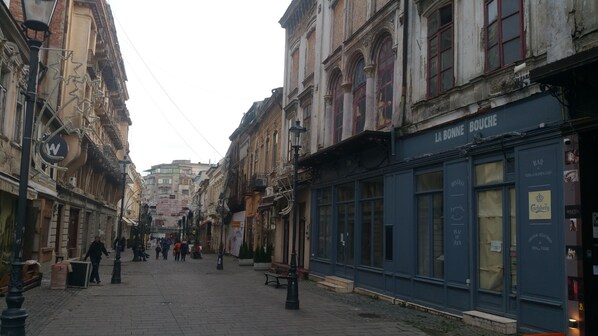 A cobblestone street lined with historic buildings, including a bar named 'La Bonne Bouche'.