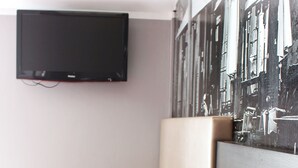 Un área de descanso moderna con un televisor de pantalla plana montado en la pared, una mesa de madera y un banco con asiento acolchado.
