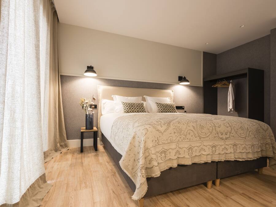 A bedroom with a large bed, bedside lamps, a nightstand, and a wardrobe.