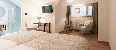 Habitación de hotel con dos camas, un escritorio, una silla, un televisor y una ventana con cortinas.