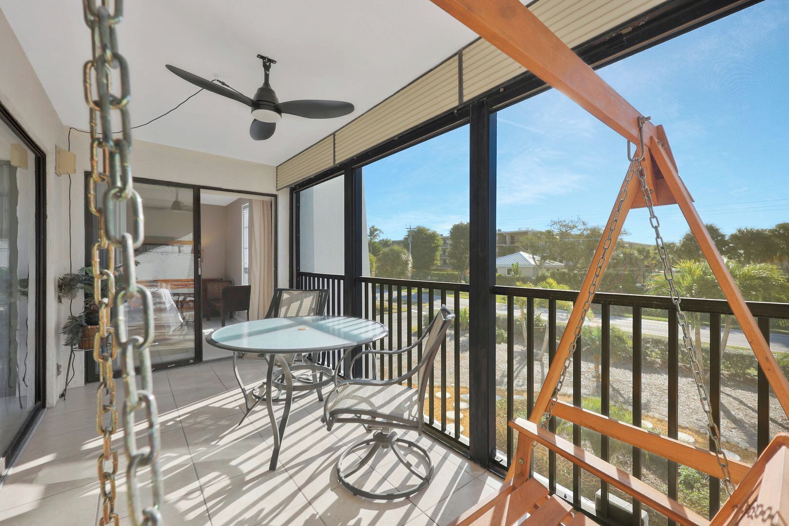 A balcony with a table and chairs, a ceiling fan, and a swing set.