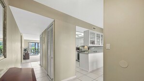 Una cocina moderna con armarios blancos, una isla central y vistas a un balcón.