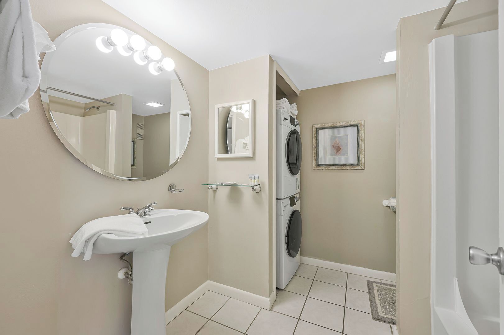 Un baño con lavabo, espejo y lavadora.