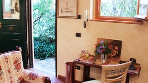 Ein Zimmer mit einer grünen Tür, einem gerahmten Bild an der Wand, einem Tisch mit Blumenvase und einem Stuhl.
