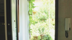 An open door leading to a tiled patio with a telephone and a wall-mounted light fixture. - Incenso Fine Studio in quiet Residence with Garden and Rooftop (Florence)