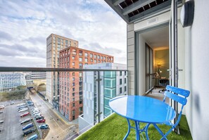 A balcony with a blue table and chair, a parking lot, and buildings in the background. - Cotels at the Hub Serviced Apartments (Milton Keynes)