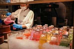 A person in a white coat and blue gloves pouring a pink liquid into a glass jar. - Park Hyatt Suzhou (Suzhou)