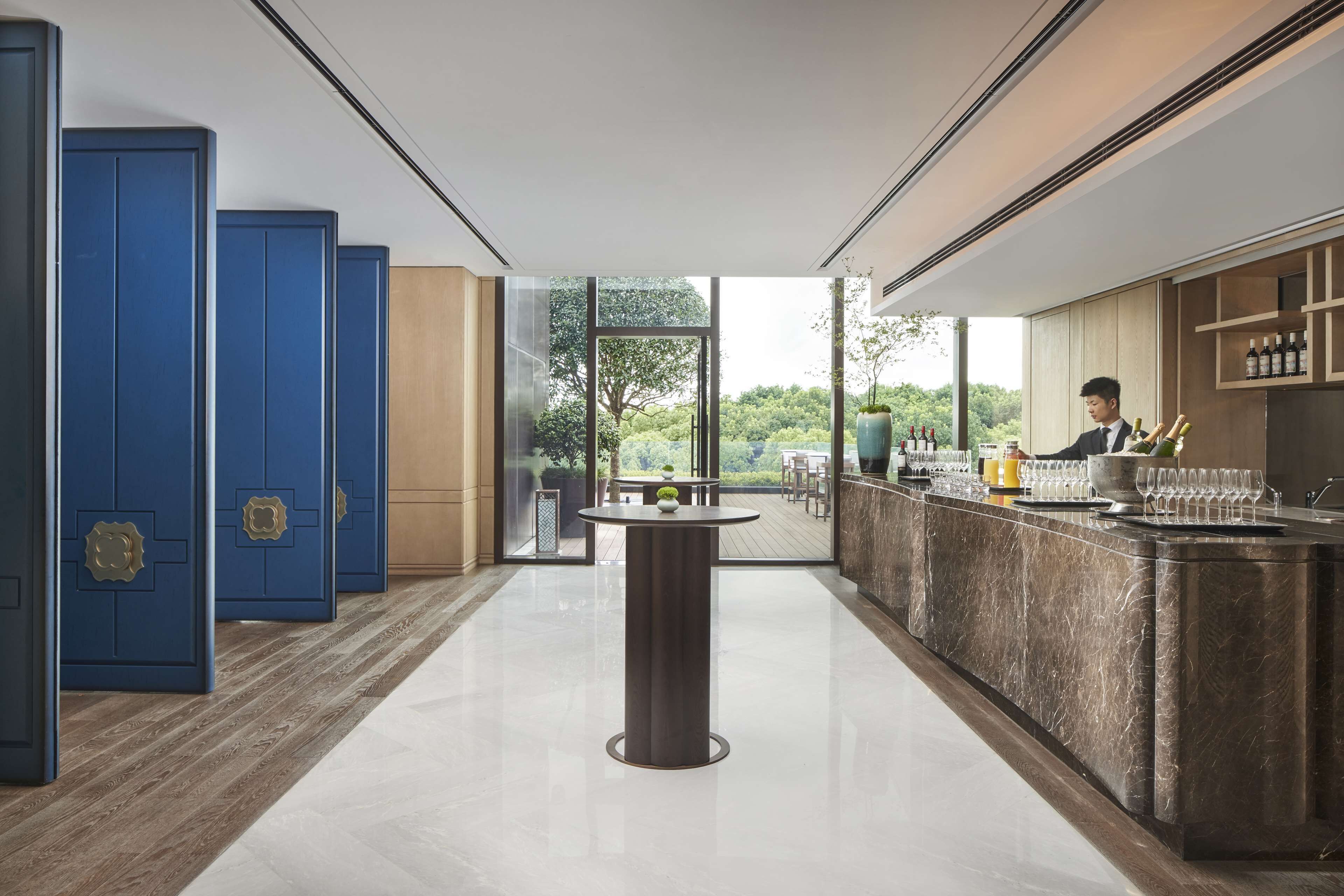 A modern bar area with a marble countertop, blue lockers, and a view of the outdoors.
