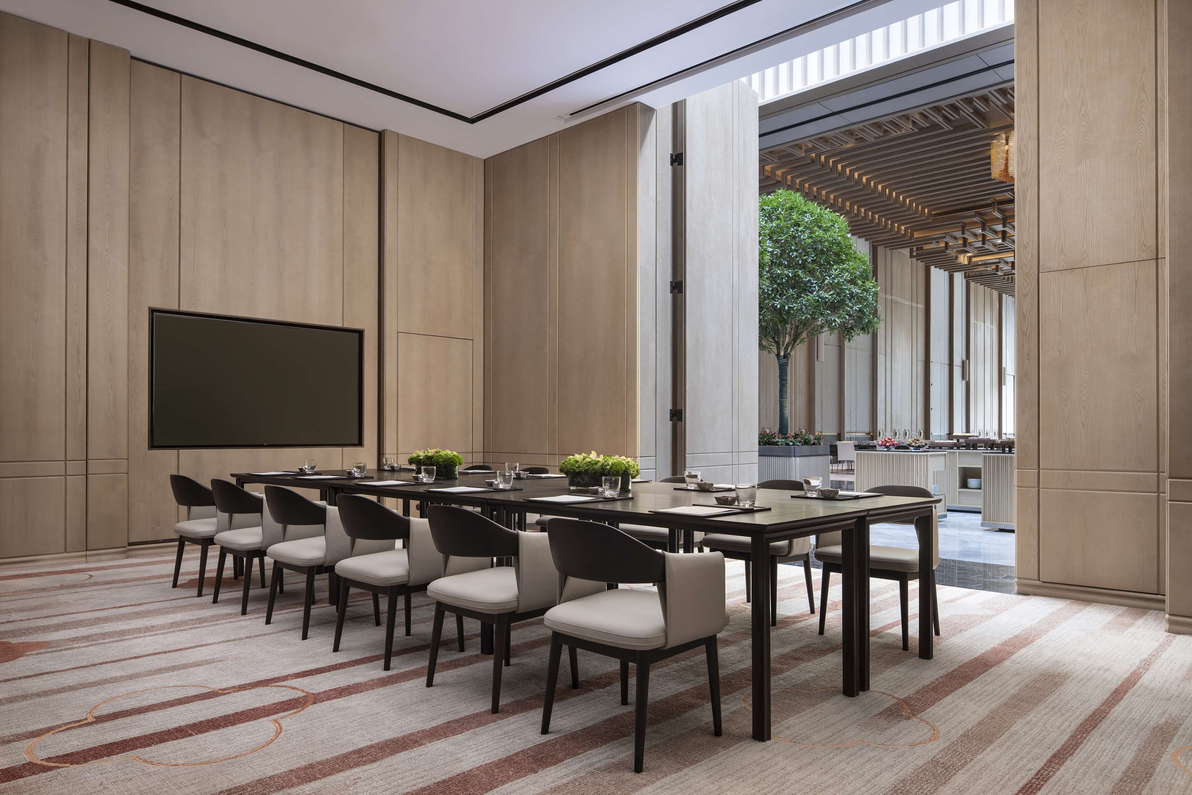 A conference room with a large screen, multiple tables, and chairs.