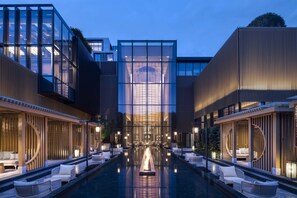 Un hotel modern amb piscina central, zones d'estar amb seients i façana de vidre.