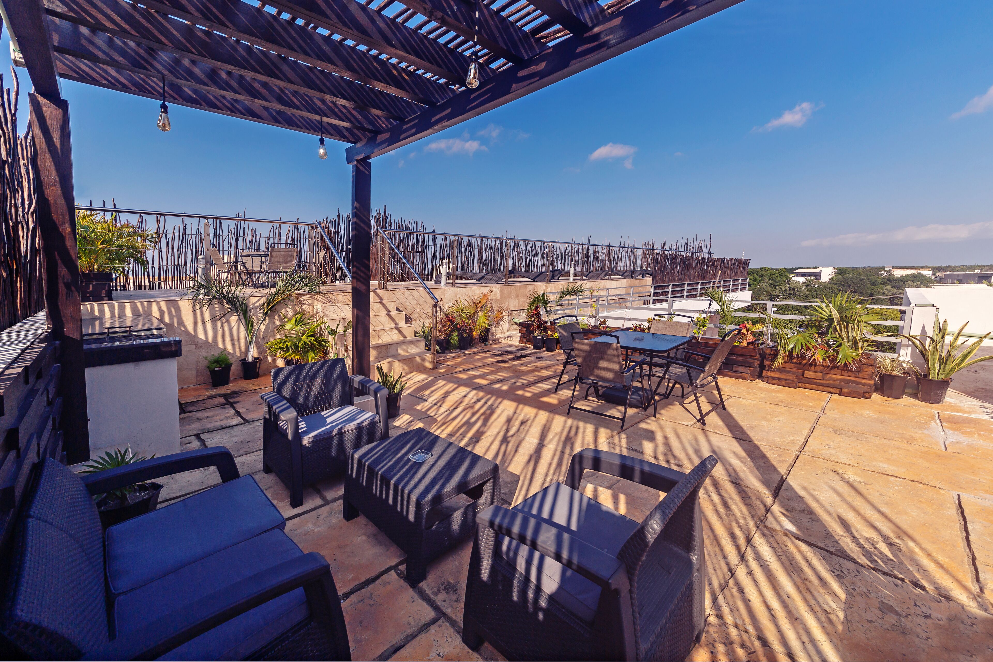 Ein Außenbereich mit Patio, Korbmöbeln, Topfpflanzen und einer Pergola.