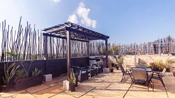Een terras op het dak met een pergola, tuinmeubilair en potplanten.