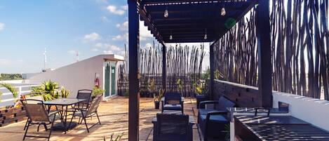 An outdoor patio with a pergola, seating area, and a grill.
