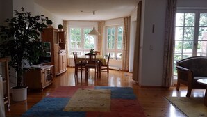 A dining area with a table and chairs, a potted plant, and a television on a cabinet.