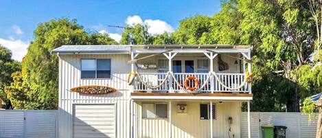 A two-story house with a balcony, a garage, and a small porch area.