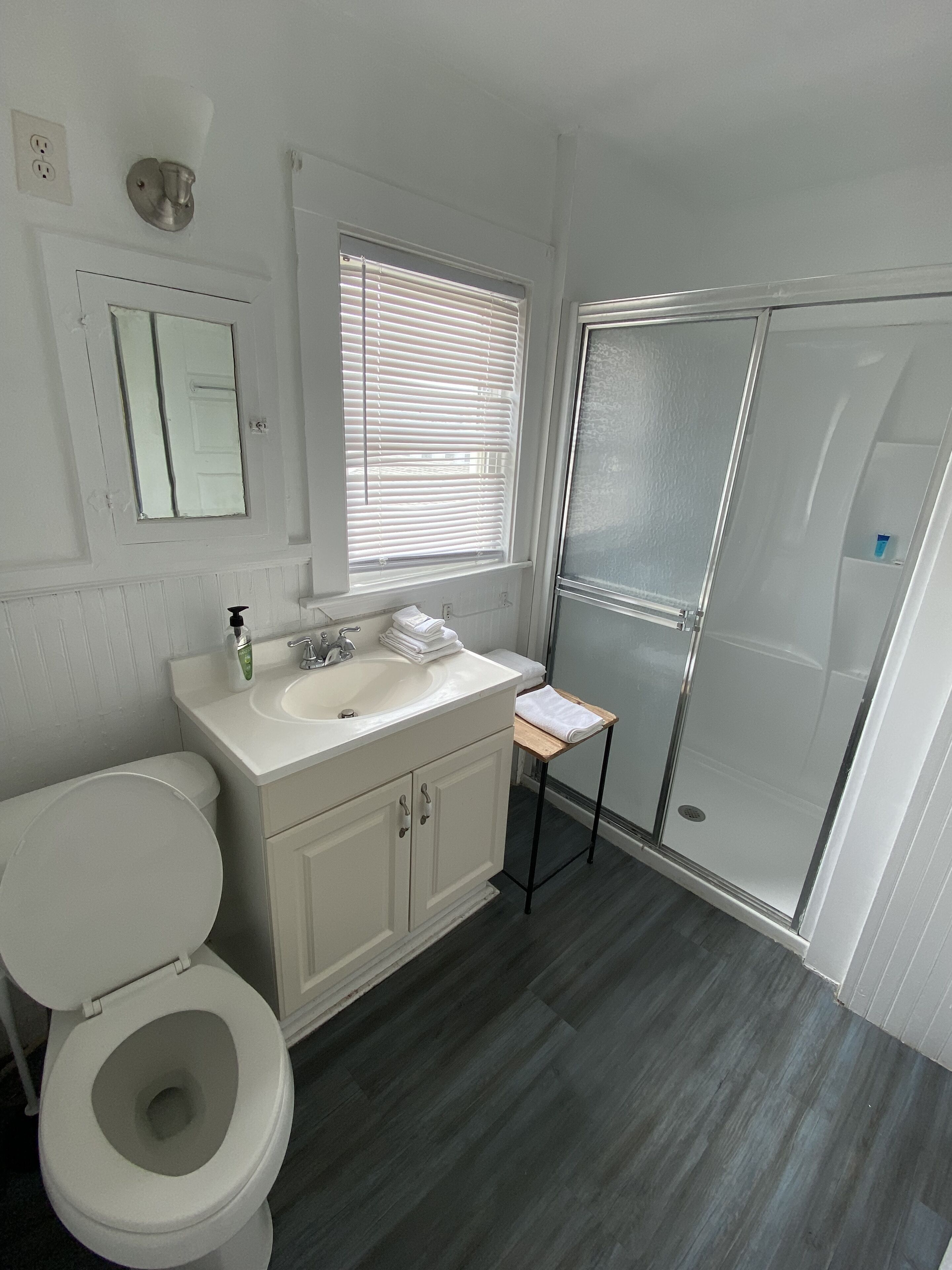 Une salle de bain équipée de toilettes, d’un lavabo, d’un miroir et d’une douche.