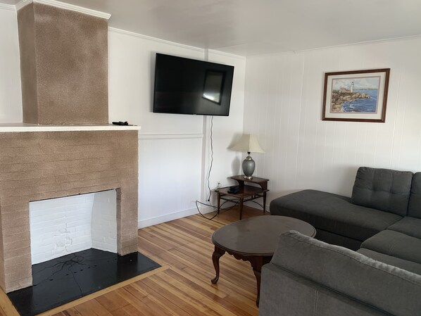 A living room with a fireplace, a flat-screen TV, a lamp, and a sofa. - Nautical Beach Resort (Hampton)