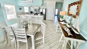 Une cuisine spacieuse avec des meubles blancs, un coin repas avec des chaises blanches et un îlot central.