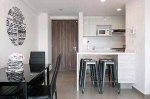 Een moderne keuken met een magnetron, fornuis en barstoelen.