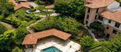 An aerial view of a residential complex with multiple buildings, a swimming pool, and surrounding greenery.