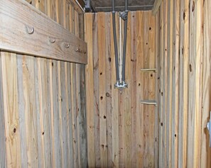 A wooden interior with a metal shower fixture and a wooden shelf.