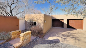 A modern house with a garage, a stone wall, and a gravel driveway.