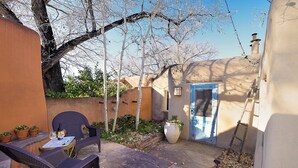 A patio with outdoor furniture, a potted plant, and a door.