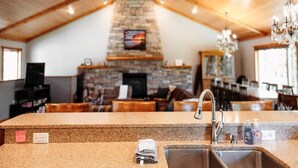 A kitchen with granite countertops, a stone fireplace, and wooden ceiling beams. - Holbrook Retreat - 5 bedroom on 47 acres (Detroit Lakes)