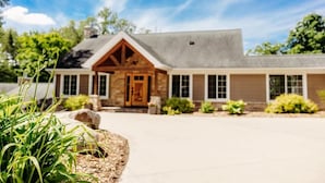 A two-story house with a stone facade, a wooden front door, and a sloped roof. - Holbrook Retreat - 5 bedroom on 47 acres (Detroit Lakes)