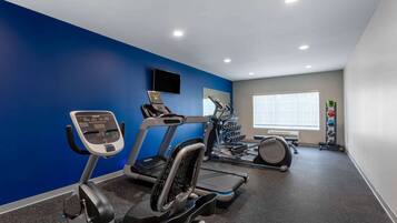 Une salle de sport équipée de tapis de course, de vélos elliptiques et de supports à poids.