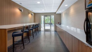 A modern kitchen with a long counter, bar stools, and a view through the glass door. - Microtel Inn & Suites by Wyndham Amsterdam (Amsterdam)